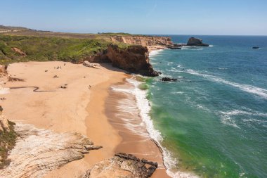 Cotoni-Coast Mandıra Eyalet Plajları 'ndaki Panther Plajı, Kaliforniya. Altın kum, dramatik uçurumlar, turkuaz dalgalar ve 1. Otoyol 'un yanındaki parlak mavi gökyüzünün altındaki manzaralı kıyı şeridi.
