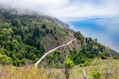 Scenic winding road along Highway 1 in Big Sur, California USA, with dramatic coastal cliffs and Pacific Ocean view, iconic travel and road trip destination on the Pacific Coast Highway