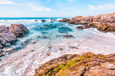 Secluded sandy beach along 17 Mile Drive in Monterey, California. Golden sand, rocky cliffs, and turquoise Pacific waters create a peaceful coastal escape on this famous scenic route
