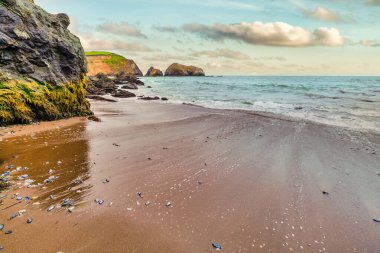 Scenic sunset view at Rodeo Beach in Marin Headlands, California. Dramatic sea stacks and ocean waves glowing in warm evening light, creating a peaceful coastal landscape along Highway 1