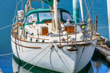 Yeşil kanopili klasik yelkenli yat marinaya yanaştı. Zarif ahşap detaylar ve denizcilik ipleri geleneksel işçiliğin altını çiziyor. Güneşli bir günde huzurlu bir liman sahnesi, seyahat ve macerayı simgeliyor.