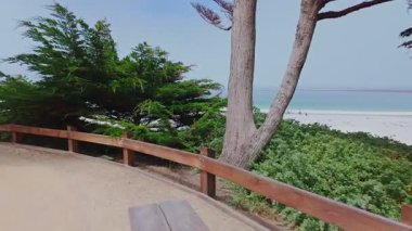 Carmel Sahili California ABD 'nin turkuaz Pasifik Okyanusu, selvi ağaçları ve deniz kenarındaki Carmel kıyı yolu ile manzaralı beyaz kumlu sahil şeridi görüntüleri, popüler seyahat ve tatil beldesi