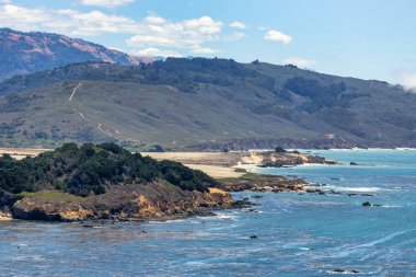 Scenic aerial view of Big Sur coastline near Point Sur Lighthouse, with turquoise Pacific waters, rugged cliffs, and rolling hills along the iconic Highway 1 in California, USA