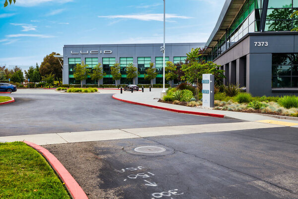 19 July 2025, Newark USA - Lucid Motors headquarters building in California USA with logo on facade and parked Lucid Air electric car in front, representing modern EV technology and innovative automotive design