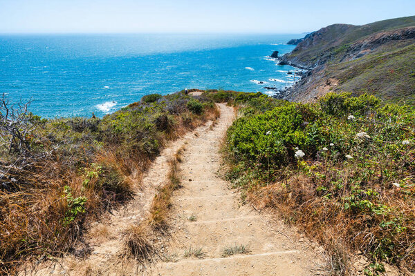 Scenic view from Tennessee Valley Trail in Marin Headlands, California. Rolling green and golden hills open toward the Pacific Ocean with distant views of San Francisco and the Bay Area skyline