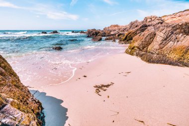 Secluded sandy beach along 17 Mile Drive in Monterey, California. Golden sand, rocky cliffs, and turquoise Pacific waters create a peaceful coastal escape on this famous scenic route