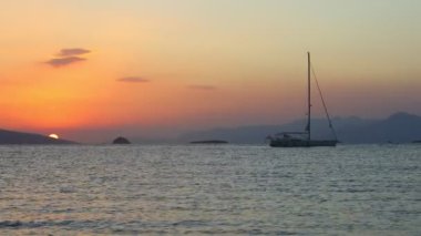 Denizde yelkenli. Denizin üzerinde deniz manzaralı altın gün doğumu. Gündoğumunda yat gezintisi. Güzel bir yelkenli ile deniz manzarası. Yelkenliyle turizm turizmi..