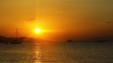 Denizde yelkenli. Denizin üzerinde deniz manzaralı altın gün doğumu. Gündoğumunda yat gezintisi. Güzel bir yelkenli ile deniz manzarası. Yelkenliyle turizm turizmi..