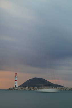 Gün ışığında deniz manzarası. Deniz feneri ve sahilde yelkenliler. Deniz kenti Turgutreis ve muhteşem güneş ışığı. Uzun pozlu çekim. Huzur sahnesi.