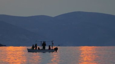 Gün batımında, balıkçı teknesinin zincirini denizden çıkarır. siluet resim.