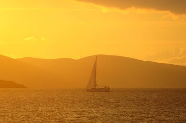 Günbatımında yalnız yelkenli. Yansımalı atmosferik deniz manzarası