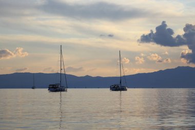 Bodrum, Turkey, 15 January 2023: Alone sailboat at sunset. Atmospheric seascape with reflection