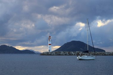 Gün ışığında deniz manzarası. Deniz feneri ve sahilde yelkenliler. Deniz kenti Turgutreis ve muhteşem güneş ışığı
