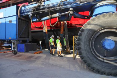 Didim, Aydin, Turkey. 20 June 2022: The huge wheel of the crane carrying the Mega yacht being maintained on land and the technician workers working next to it. 