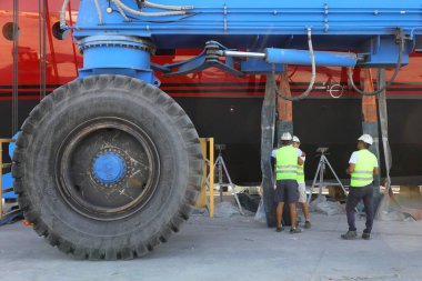 Didim, Aydin, Turkey. 20 June 2022: The huge wheel of the crane carrying the Mega yacht being maintained on land and the technician workers working next to it. 