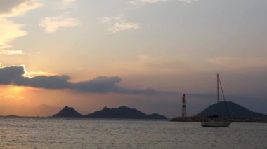 Gün ışığında deniz manzarası. Deniz feneri ve sahilde yelkenliler. Deniz kenti Turgutreis ve muhteşem güneş ışığı