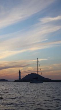Gün batımında deniz manzarası. Sahildeki deniz feneri. Deniz kenti Turgutreis ve muhteşem gün batımları. Sosyal medya için dikey video