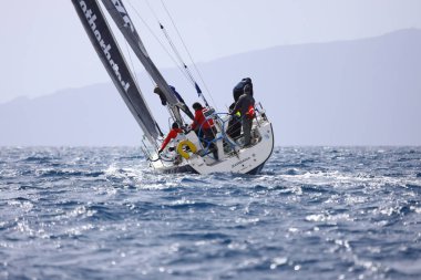 Bodrum, Hindi. 12 Mart 2023: Yelkenliler Ege Denizi 'nin mavi sularında, ünlü tatil beldesi Bodrum' un kıyılarında rüzgarlı havada yelken açıyorlar..