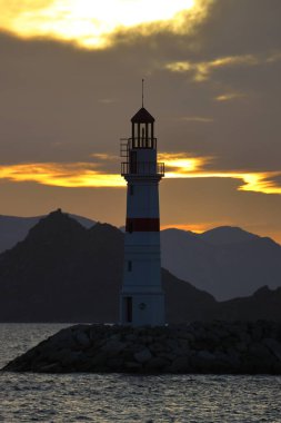 Gün ışığında deniz manzarası. Deniz feneri ve sahilde yelkenliler. Deniz kenti Turgutreis ve muhteşem güneş ışığı