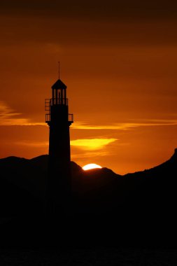 Gün ışığında deniz manzarası. Deniz feneri ve sahilde yelkenliler. Deniz kenti Turgutreis ve muhteşem güneş ışığı