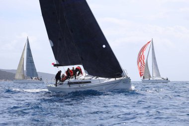 Bodrum, Hindi. 12 Mart 2023: Yelkenliler Ege Denizi 'nin mavi sularında, ünlü tatil beldesi Bodrum' un kıyılarında rüzgarlı havada yelken açıyorlar..