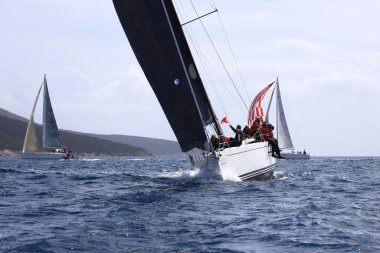 Bodrum, Hindi. 12 Mart 2023: Yelkenliler Ege Denizi 'nin mavi sularında, ünlü tatil beldesi Bodrum' un kıyılarında rüzgarlı havada yelken açıyorlar..