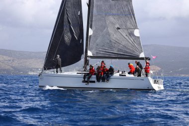 Bodrum, Hindi. 12 Mart 2023: Yelkenliler Ege Denizi 'nin mavi sularında, ünlü tatil beldesi Bodrum' un kıyılarında rüzgarlı havada yelken açıyorlar..