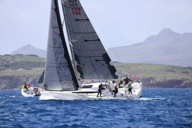 Bodrum, Hindi. 12 Mart 2023: Yelkenliler Ege Denizi 'nin mavi sularında, ünlü tatil beldesi Bodrum' un kıyılarında rüzgarlı havada yelken açıyorlar..