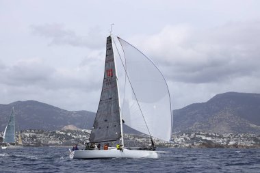 Bodrum, Hindi. 01 Nisan 2023: Ege Denizi 'nin mavi sularında, ünlü tatil beldesi Bodrum' un kıyılarında, rüzgarlı havada yelkenliler yelken açıyor.