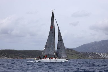 Bodrum, Hindi. 01 Nisan 2023: Ege Denizi 'nin mavi sularında, ünlü tatil beldesi Bodrum' un kıyılarında, rüzgarlı havada yelkenliler yelken açıyor.