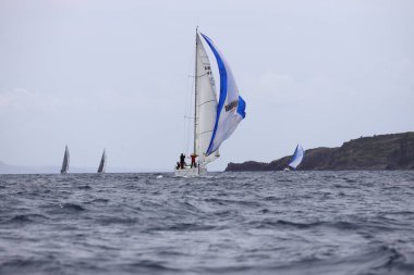 Bodrum, Hindi. 01 Nisan 2023: Ege Denizi 'nin mavi sularında, ünlü tatil beldesi Bodrum' un kıyılarında, rüzgarlı havada yelkenliler yelken açıyor.