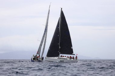 Bodrum, Hindi. 01 Nisan 2023: Ege Denizi 'nin mavi sularında, ünlü tatil beldesi Bodrum' un kıyılarında, rüzgarlı havada yelkenliler yelken açıyor.