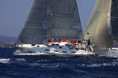 Bodrum, Hindi. 07 Mayıs 2023: Ege Denizi 'nin mavi sularında, ünlü tatil beldesi Bodrum' un kıyılarında yelkenliler rüzgarlı havada yelken açıyor.