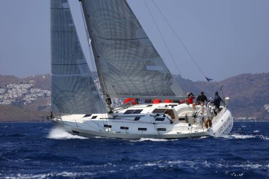 Bodrum, Hindi. 07 Mayıs 2023: Ege Denizi 'nin mavi sularında, ünlü tatil beldesi Bodrum' un kıyılarında yelkenliler rüzgarlı havada yelken açıyor.