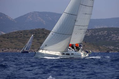 Bodrum, Hindi. 07 Mayıs 2023: Ege Denizi 'nin mavi sularında, ünlü tatil beldesi Bodrum' un kıyılarında yelkenliler rüzgarlı havada yelken açıyor.