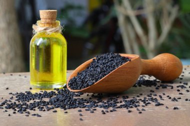 Siyah kimyon tohumları ve kase, tahta kürek ya da kaşık ile gerekli yağ. Nigella Sativa cam şişede. Birçok hastalık için organik bitkisel ilaç