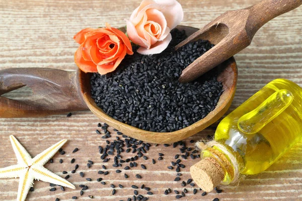 Stock image Black cumin seeds and essential oil with bowl and wooden shovel or spoon. Nigella Sativa in glass bottle. Organic herbal medicine for many diseases