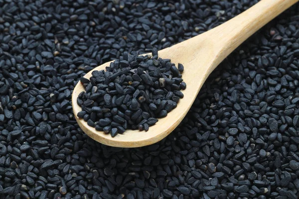 stock image Black cumin seeds and essential oil with bowl and wooden shovel or spoon. Nigella Sativa in glass bottle. Organic herbal medicine for many diseases