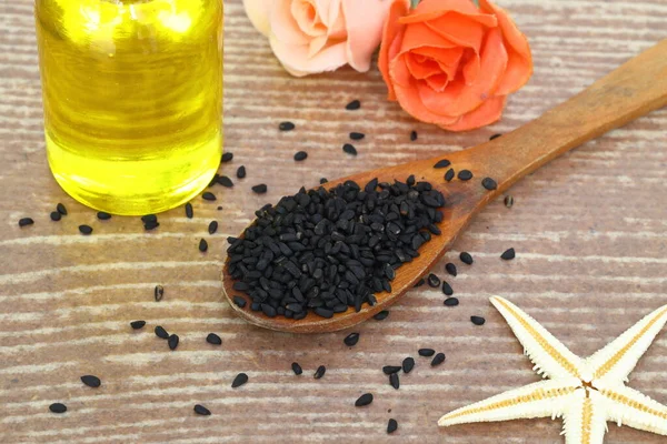 stock image Black cumin seeds and essential oil with bowl and wooden shovel or spoon. Nigella Sativa in glass bottle. Organic herbal medicine for many diseases