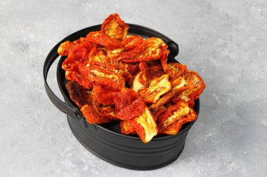 Tahta arka planda kurutulmuş domates kasesi. Taze ot ve baharatla kurutulmuş domates. Sonbahar mevsimi turşusu ya da fermente edilmiş renkli sebzeler. Lezzetli kurutulmuş domates.