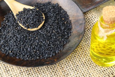 Siyah kimyon tohumları ve kase, tahta kürek ya da kaşık ile gerekli yağ. Nigella Sativa cam şişede. Birçok hastalık için organik bitkisel ilaç