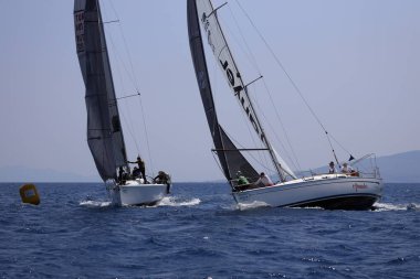 Bodrum, Hindi. 07 Mayıs 2023: Ege Denizi 'nin mavi sularında, ünlü tatil beldesi Bodrum' un kıyılarında yelkenliler rüzgarlı havada yelken açıyor.