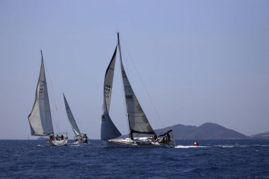 Bodrum, Hindi. 07 Mayıs 2023: Ege Denizi 'nin mavi sularında, ünlü tatil beldesi Bodrum' un kıyılarında yelkenliler rüzgarlı havada yelken açıyor.
