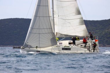 Bodrum, Hindi. 16 Nisan 2023: Yelkenliler Ege Denizi 'nin mavi sularında, ünlü tatil beldesi Bodrum' un kıyılarında rüzgarlı havada yelken açıyor..