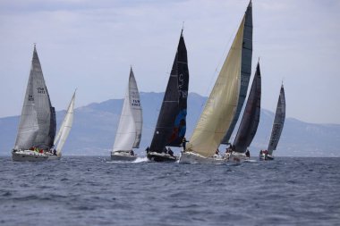 Bodrum, Hindi. 16 Nisan 2023: Yelkenliler Ege Denizi 'nin mavi sularında, ünlü tatil beldesi Bodrum' un kıyılarında rüzgarlı havada yelken açıyor..