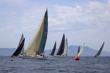 Bodrum, Hindi. 16 Nisan 2023: Yelkenliler Ege Denizi 'nin mavi sularında, ünlü tatil beldesi Bodrum' un kıyılarında rüzgarlı havada yelken açıyor..
