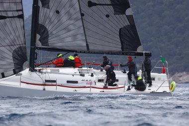 Bodrum, Hindi. 16 Nisan 2023: Yelkenliler Ege Denizi 'nin mavi sularında, ünlü tatil beldesi Bodrum' un kıyılarında rüzgarlı havada yelken açıyor..