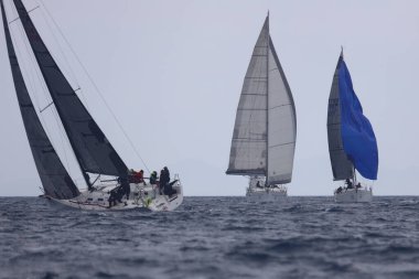 Bodrum, Hindi. 16 Nisan 2023: Yelkenliler Ege Denizi 'nin mavi sularında, ünlü tatil beldesi Bodrum' un kıyılarında rüzgarlı havada yelken açıyor..