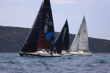 Bodrum, Hindi. 16 Nisan 2023: Yelkenliler Ege Denizi 'nin mavi sularında, ünlü tatil beldesi Bodrum' un kıyılarında rüzgarlı havada yelken açıyor..