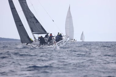 Bodrum, Hindi. 16 Nisan 2023: Yelkenliler Ege Denizi 'nin mavi sularında, ünlü tatil beldesi Bodrum' un kıyılarında rüzgarlı havada yelken açıyor..